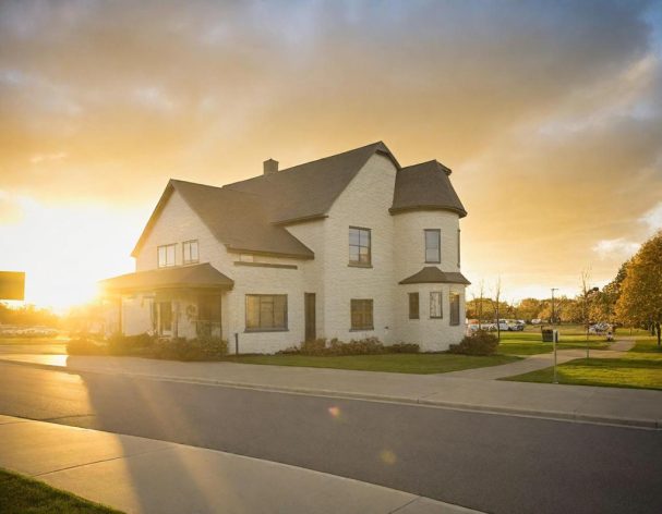 SEARCH WAYNE COUNTY A two-story house with a white exterior, bathed in golden sunset light.